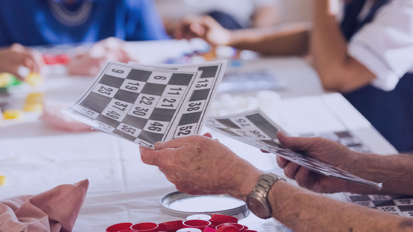 mãos do homem sênior distribuindo cartões numéricos para um jogo de bingo