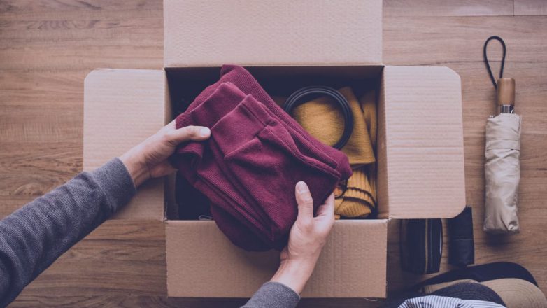 Filantropia: Limpeza da casa e conceitos de doação com jovens colocando roupas de acessórios em uma caixa marrom.
