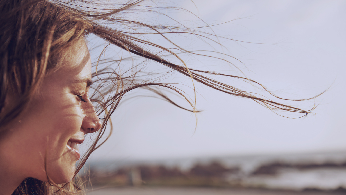Humor de cada signo: Imagem recortada de uma jovem com o vento em seus cabelos